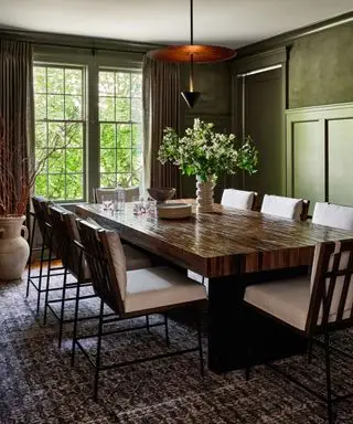 Salle à manger verte avec suspension basse, table à manger et chaises en bois sombre