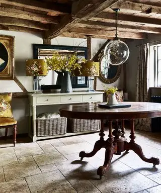 타일 ​​바닥과 앤티크 가구를 갖춘 오래된 기둥이 있는 시골 별장의 복도