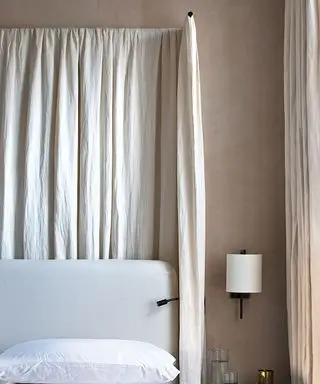 Chambre neutre avec auvent crème. Literie blanche, murs peints en beige