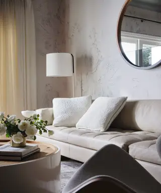 Un salon avec un canapé blanc et des fleurs blanches