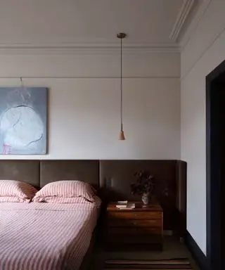 빨간색 줄무늬 침구와 확장된 짙은 갈색 머리판이 있는 점토색 침실