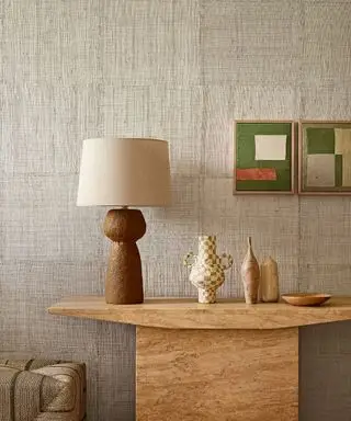 Nøytral, strukturert tapet, kremfinish, konsollbord i marmor, to rosa og grønne abstrakte trykk, høy bordlampe med flytende, buet base, kremskjerm,