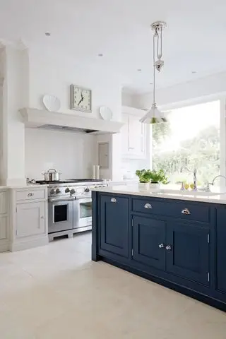 Cocina blanca con isla azul de Tom Howley