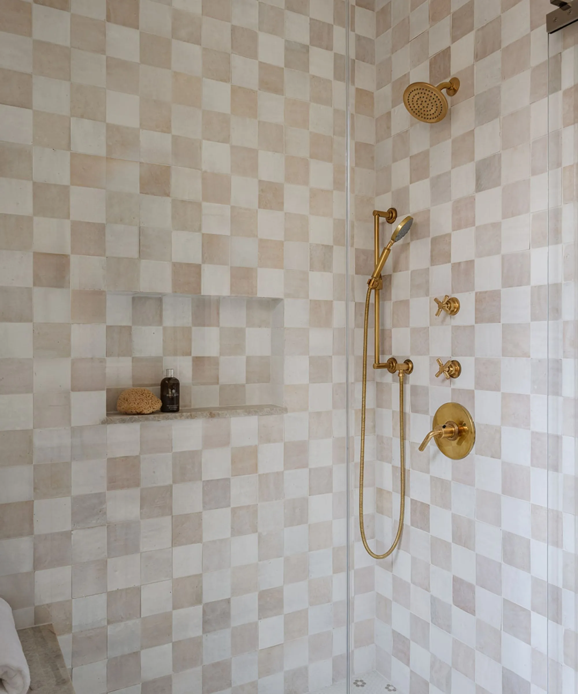 ゴールドの金具とチェッカーボードのクリームとピンクのタイルを備えたウォークインシャワー' loading='lazy' title=