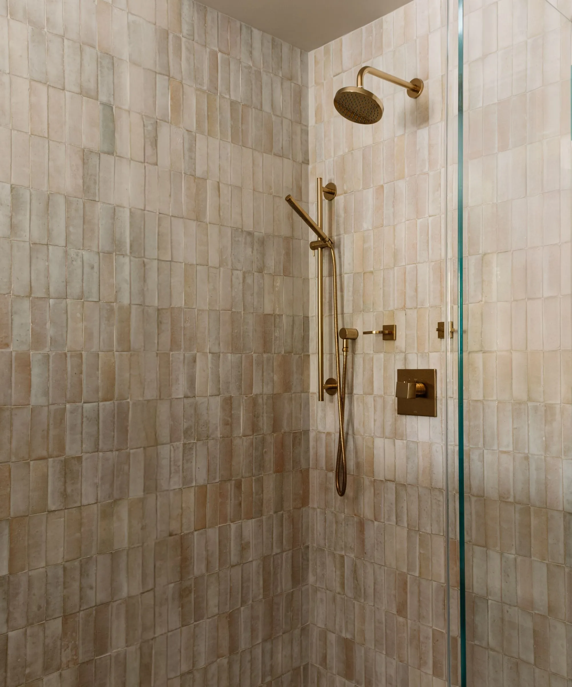 ゴールドの金具とベージュのテクスチャータイルを備えたウォークインシャワー' loading='lazy' title=