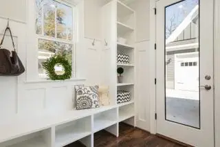 Un petit vestiaire blanc avec une fenêtre, une banquette et une porte vitrée