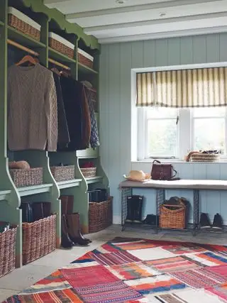 Un exemple d'idées de vestiaire montrant un tapis de sol aux motifs brillants et un espace de rangement vert avec des paniers en osier