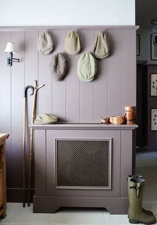 Murs lambrissés en bois violet dans un vestiaire avec des bottes en caoutchouc au sol et des chapeaux accrochés au mur