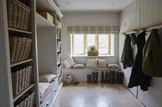 Un exemple d'idées de vestiaire montrant un vestiaire avec une banquette avec des coussins sous une fenêtre et des rangements muraux et des patères