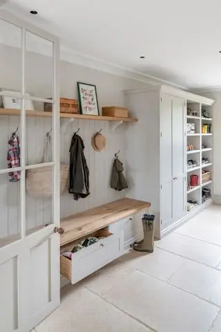 Une idée de vestiaire lumineux et aéré avec une banquette en bois, des tiroirs coulissants et des patères