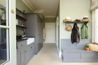 Un grand vestiaire avec des armoires grises et un banc en bois gris sous des patères