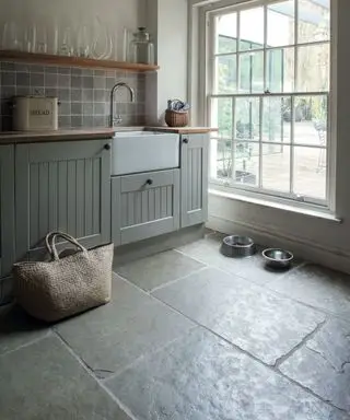 Un vestiaire sombre avec deux gamelles pour chiens, un coin lavabo et une grande fenêtre