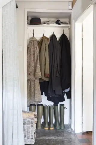 Un petit dressing transformé en vestiaire avec des bottes en caoutchouc et des manteaux