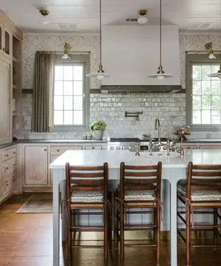 cucina rustica verde chiaro con pavimento in legno scuro e sgabelli da bar in legno scuro in una stanza altrimenti dai colori chiari