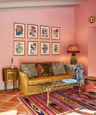 korálový/růžový obývací pokoj se zlatou pohovkou, uměleckým dílem, zlatým odkládacím stolkem, lampou, vícebarevným kobercem