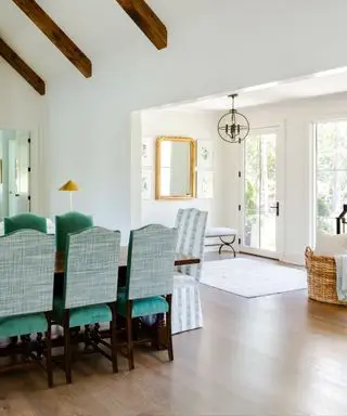 En hvid entré og spisestue med grønne fløjlsstole.