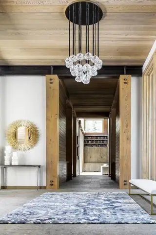 entrée avec sol carrelé en pierre, tapis, plafond et murs en bois, lustre, miroir, console