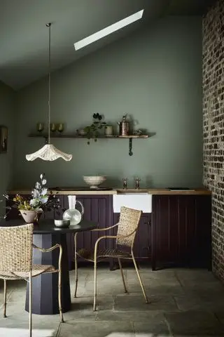 Cuisine de salle à manger en bois sombre avec mur vert sauge et suspension en rotin