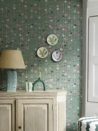 papier peint rose et vert derrière la console avec plaques sur mur et lampe