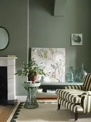 salon avec murs vert sauge, cheminée en marbre et chaise à rayures vertes