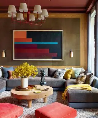 gemütliche Ecke mit grauem U-förmigem Sofa und braunen Wänden mit Kunst