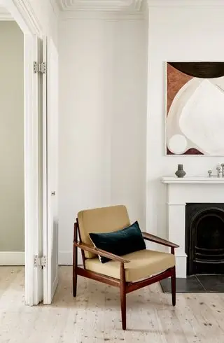 Salón blanco con sillón de mediados de siglo.