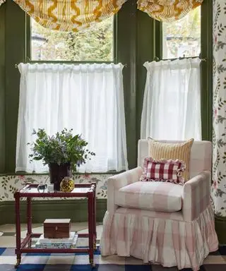 Salon coloré, stores jaunes, murs peints en vert, fauteuil à carreaux roses et blancs, papier peint fleuri, tapis à motifs bleus