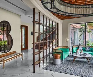 Couloir-salon moderne et ouvert avec cloison en bois, tapis géométrique sur carrelage et table basse angulaire sous