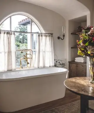 baño blanco con bañera independiente y ventana arqueada