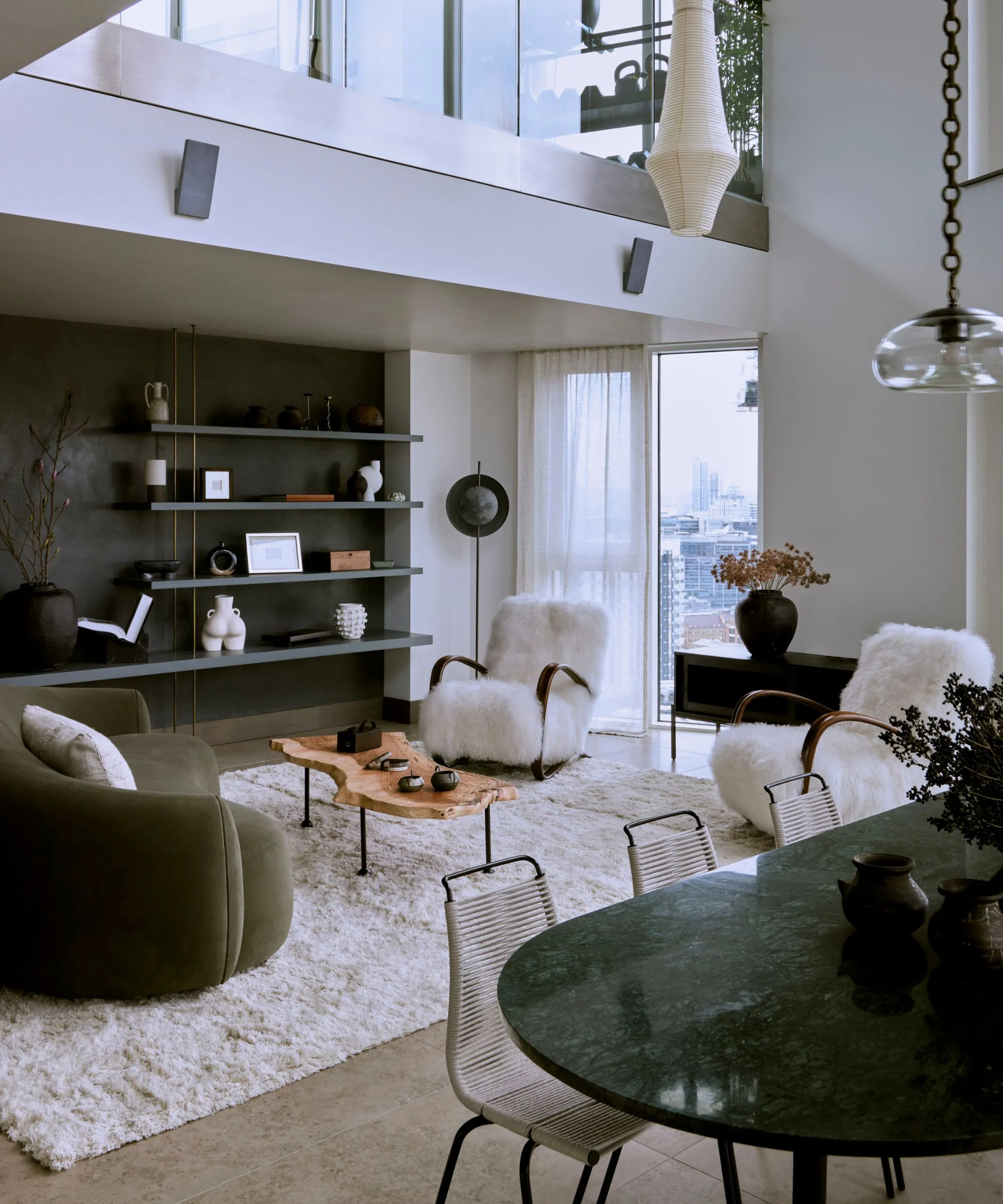 식당이있는 아늑한 현대 오픈 플랜 거실 공간 녹색 대리석 테이블 현대 의자 녹색 벨벳 구부러진 소파와 양가죽 팔 의자가있는 흰색 푹신한 깔개가있는 넓은 거실 공간' loading='lazy' title=