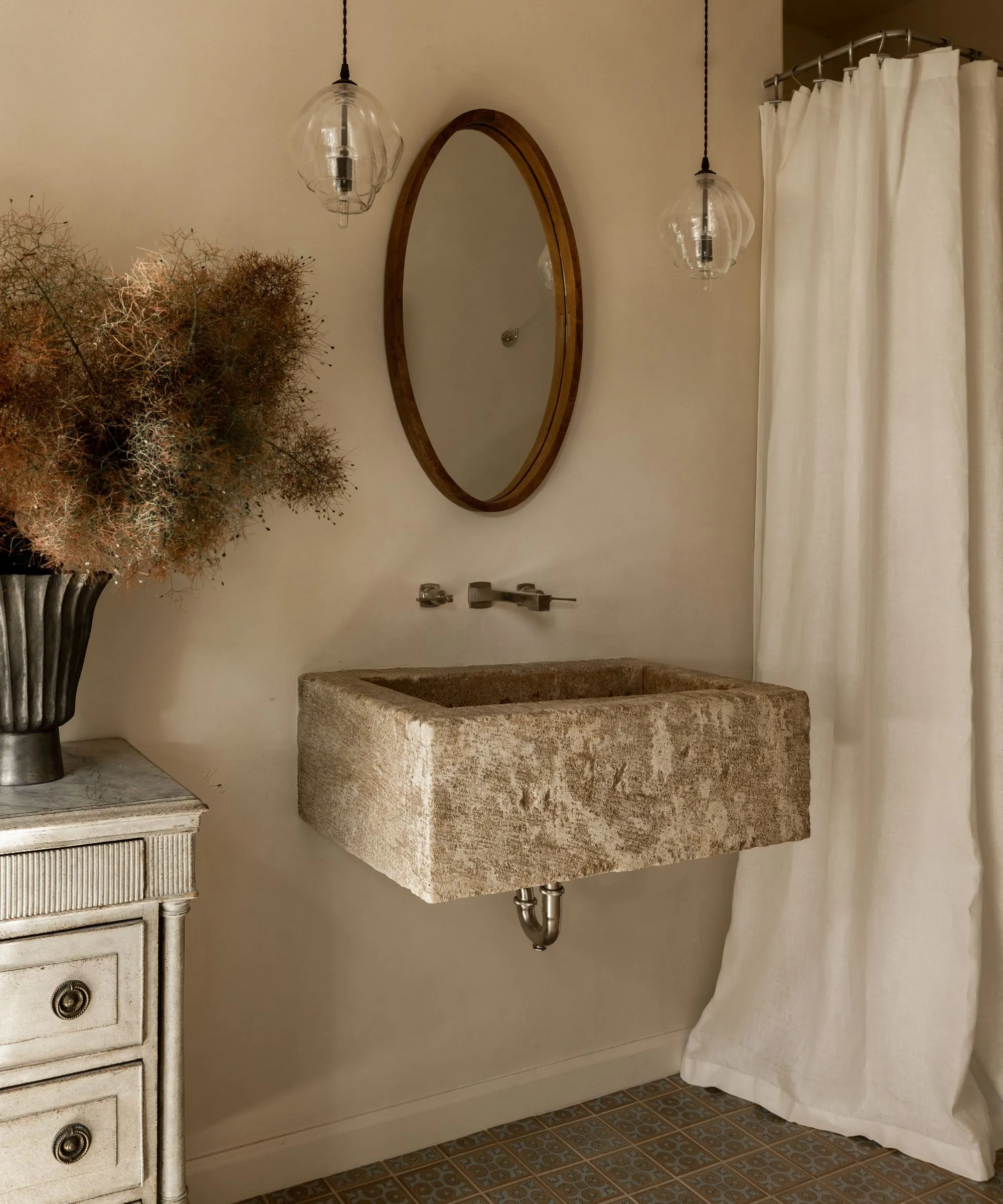 흰색 린넨 샤워 커튼 돌로 부유 한 싱크 나무 거울과 가지가있는 꽃병이있는 골동품 드레서와 따뜻한 중성 작은 욕실' loading='lazy' title=