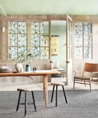 회색 러그 위에 나무 테이블, 의자, 스툴, 나무 클래드, 녹색 페인트 천장을 갖춘 식당입니다.