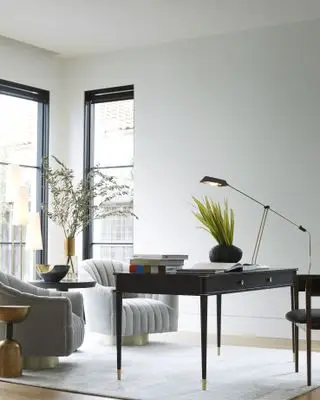 Bureau à domicile monochrome avec fauteuils gris, bureau et chaise noirs, lampe de bureau noire, tapis gris pâle, fenêtres crittall noires