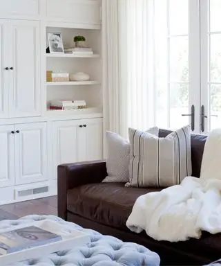 Roh bielej obývačky s hnedým koženým gaučom a svetlomodrým futónom