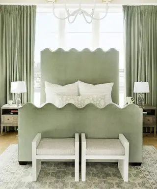 큰 창문과 나무 바닥이 있는 침실에 가리비 디테일이 있는 연한 녹색 침대