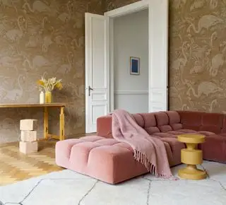 sala de estar con papel tapiz estampado beige, sofá coral y alfombra color crema