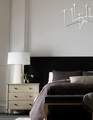Chambre blanche avec tête de lit noire et commode en bois par Arteriors