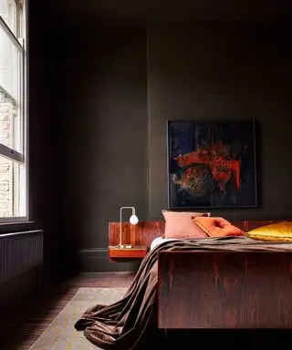 Chambre marron avec oreillers orange, murs peints en marron et parquet