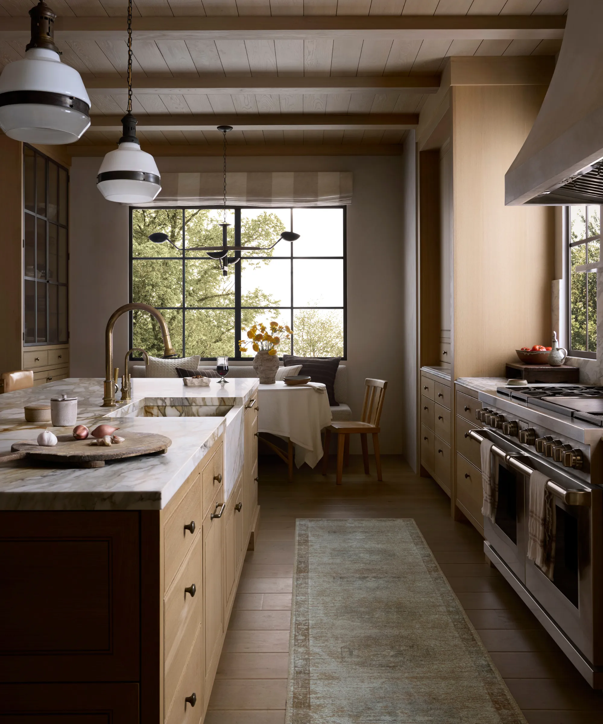 大理石のカウンタートップのある大きな島のあるキッチンランナーの敷物と大きなオーブンを備えたキッチン' loading='lazy' title=