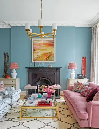 Salon bleu avec cheminée noire et tissus d'ameublement roses