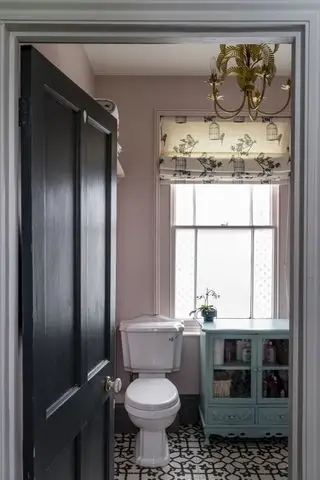 salle de bains rose avec carrelage à motifs et porte noire, store imprimé