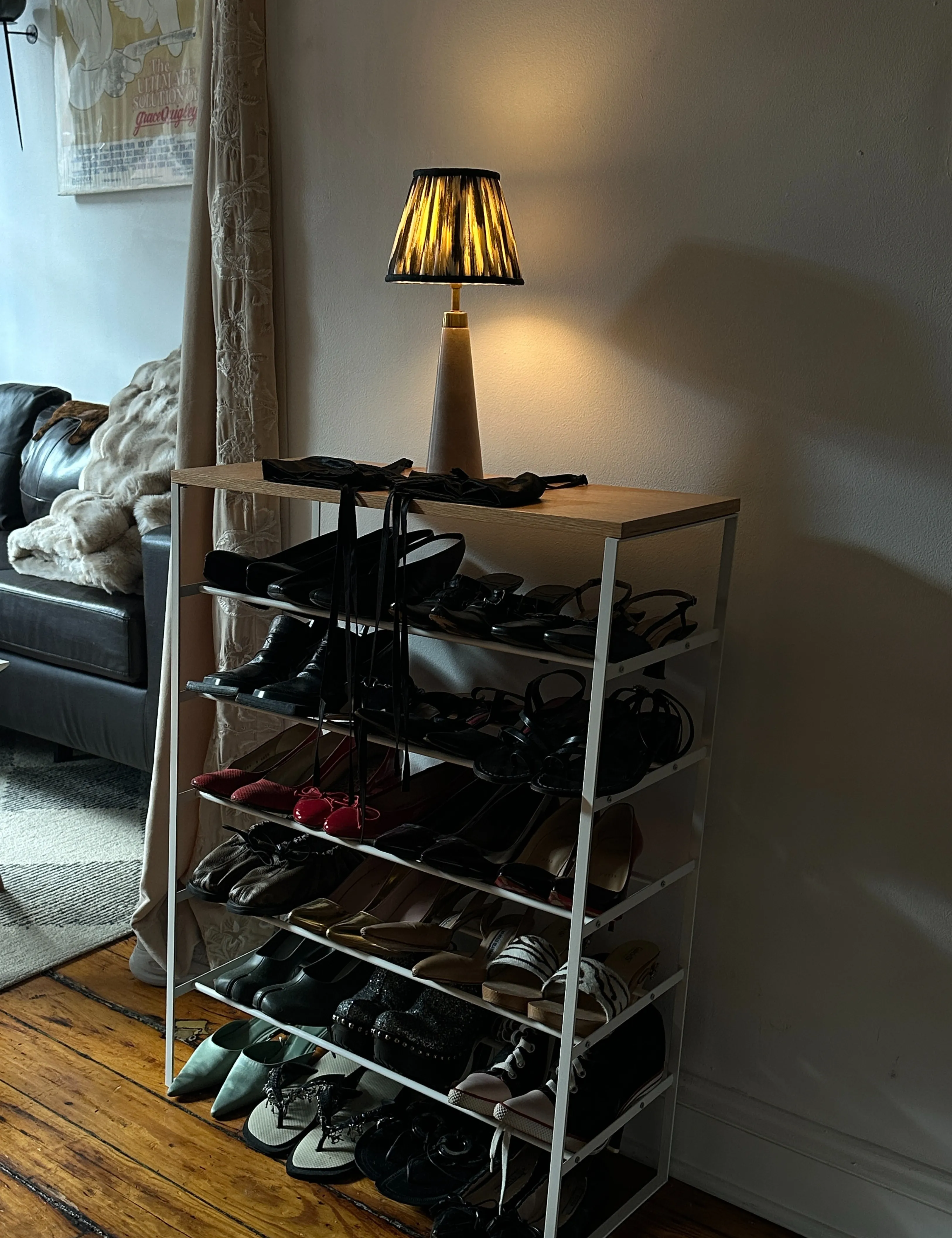 Ikat skyggefuld Pooky -bordlampe, der hviler oven på et skoholder i en svagt oplyst stue' loading='lazy' title=