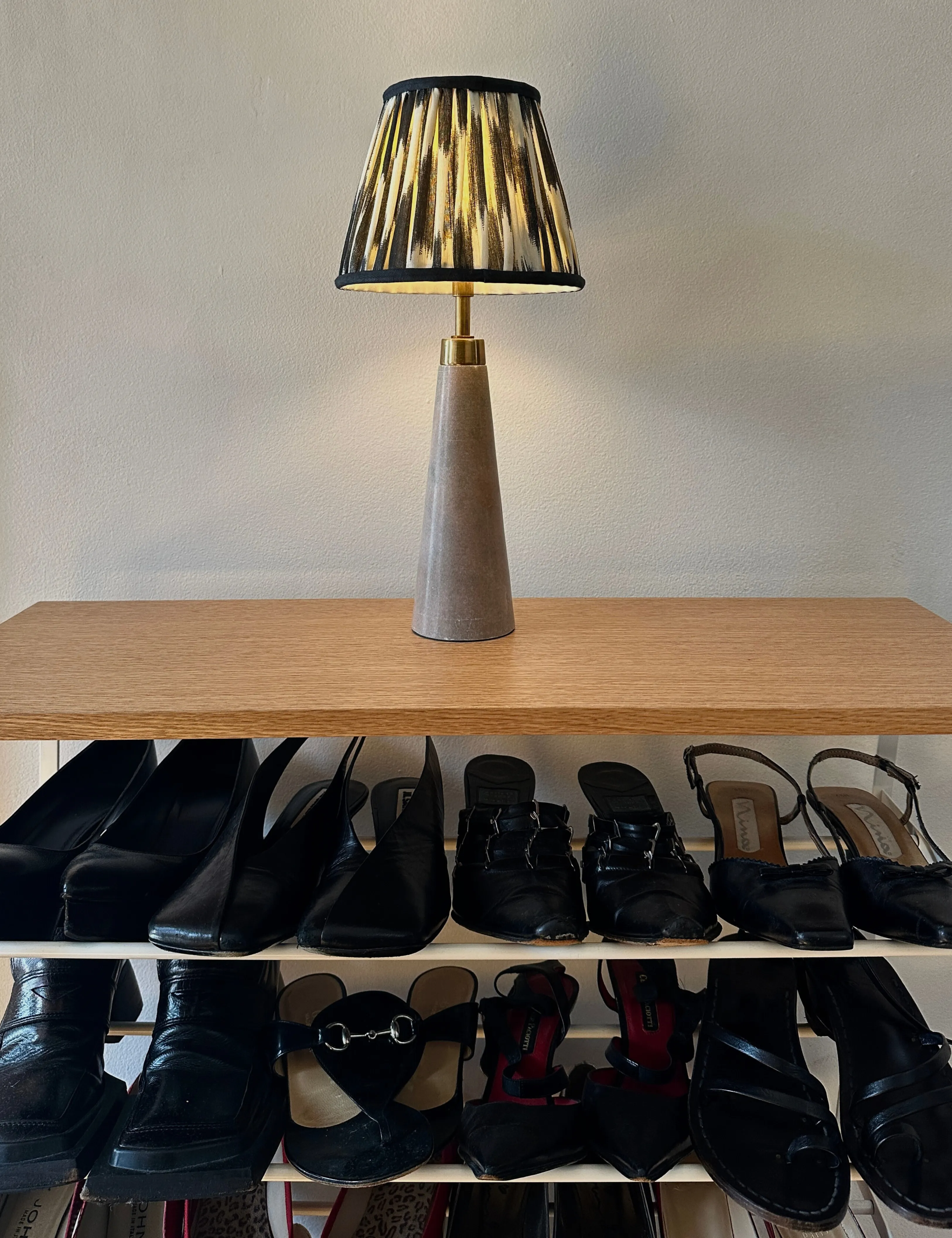 Ikat skyggede bordlampe, der hviler på toppen af ​​et træsko rack' loading='lazy' title=