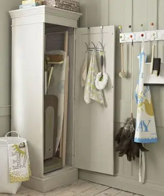 アイロン台を収納した背の高いベージュのキャビネットを備えたランドリー ルーム