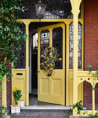 Porche d'entrée jaune avec couronne de printemps, lanterne traditionnelle, vitraux, carreaux à motifs