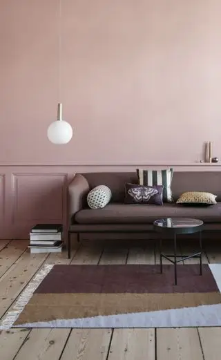 Canapé en cuir marron foncé contre un mur rose