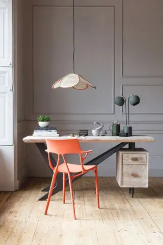 oficina en casa con paneles de pared, suelo de madera, silla moderna de color naranja, escritorio de madera y metal, luz colgante, lámpara de escritorio
