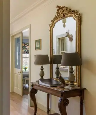 Couloir avec table en bois de style français et miroir encadré orné sur mur neutre