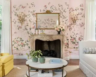 Smuk pink stue med blomstertapet, dekoreret pejs