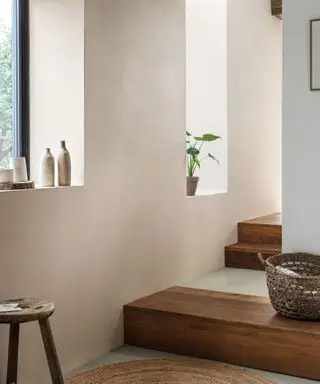 Espace de couloir neutre et décontracté, parquet, grandes fenêtres, marches menant à une autre pièce, panier tressé au sol